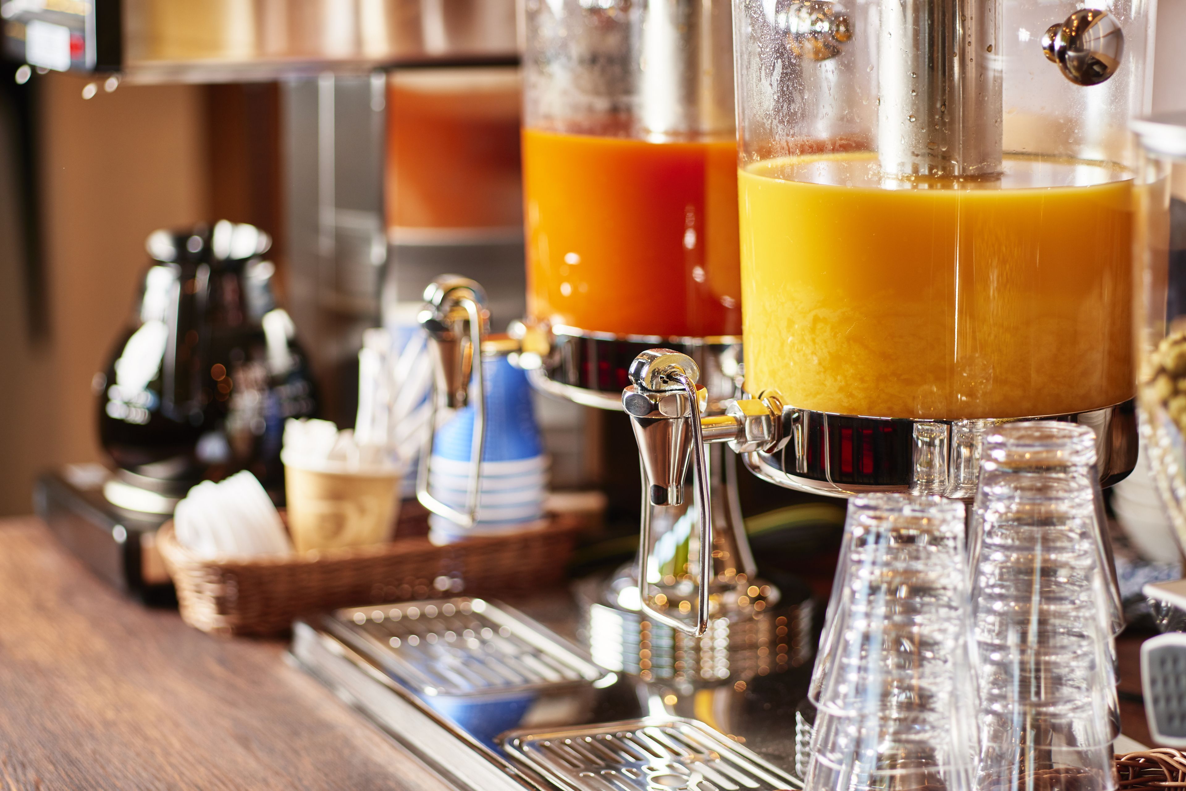 A coffee machine with multiple dispensers, a basket with napkins, and a metal tray.