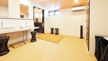 Un bagno moderno con soffitto in legno, due lavabi, uno specchio grande e un cestino nero.