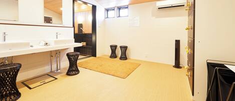 Un baño moderno con techo de madera, dos lavamanos, un espejo grande y un cesto de basura negro.