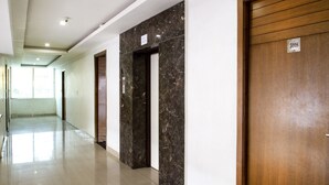 A hallway with marble walls, wooden doors, and a clean, tiled floor. - Rainbow International Shamshabad (Hyderabad)