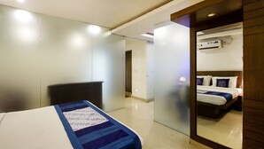 A modern hotel room with a bed, a desk, and a mirror reflecting the room. - Rainbow International Shamshabad (Hyderabad)