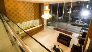 A lobby with a reception desk, a sofa, and a chandelier. - Rainbow International Shamshabad (Hyderabad)