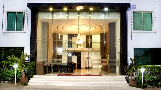 A hotel entrance with a glass facade, a reception desk, and a chandelier. - Rainbow International Shamshabad (Hyderabad)