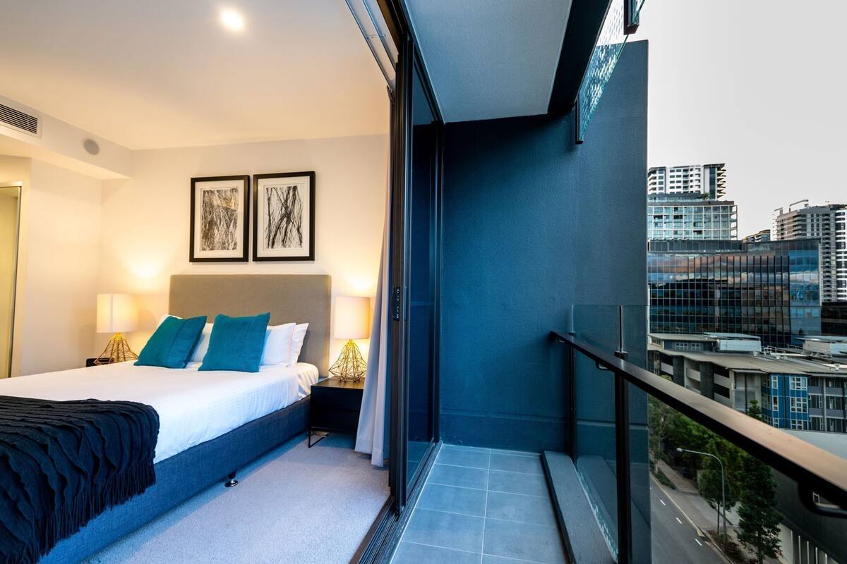 Una habitación de hotel moderna con una cama grande, dos lámparas de noche y cuadros en la pared.