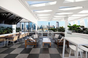 Un salon moderne offrant une vue sur la ville, avec un sol à carreaux, des meubles en bois et des plantes en pot.