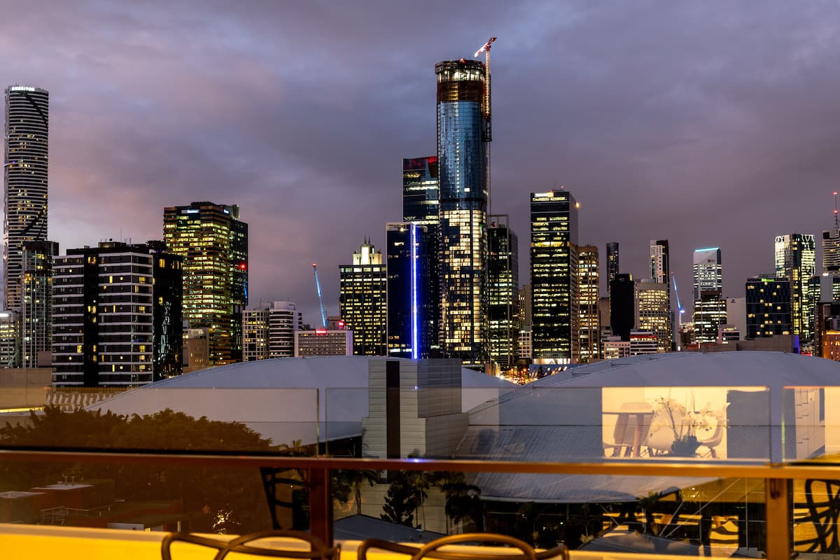 Un horizonte urbano al anochecer con edificios iluminados y una grúa de construcción.