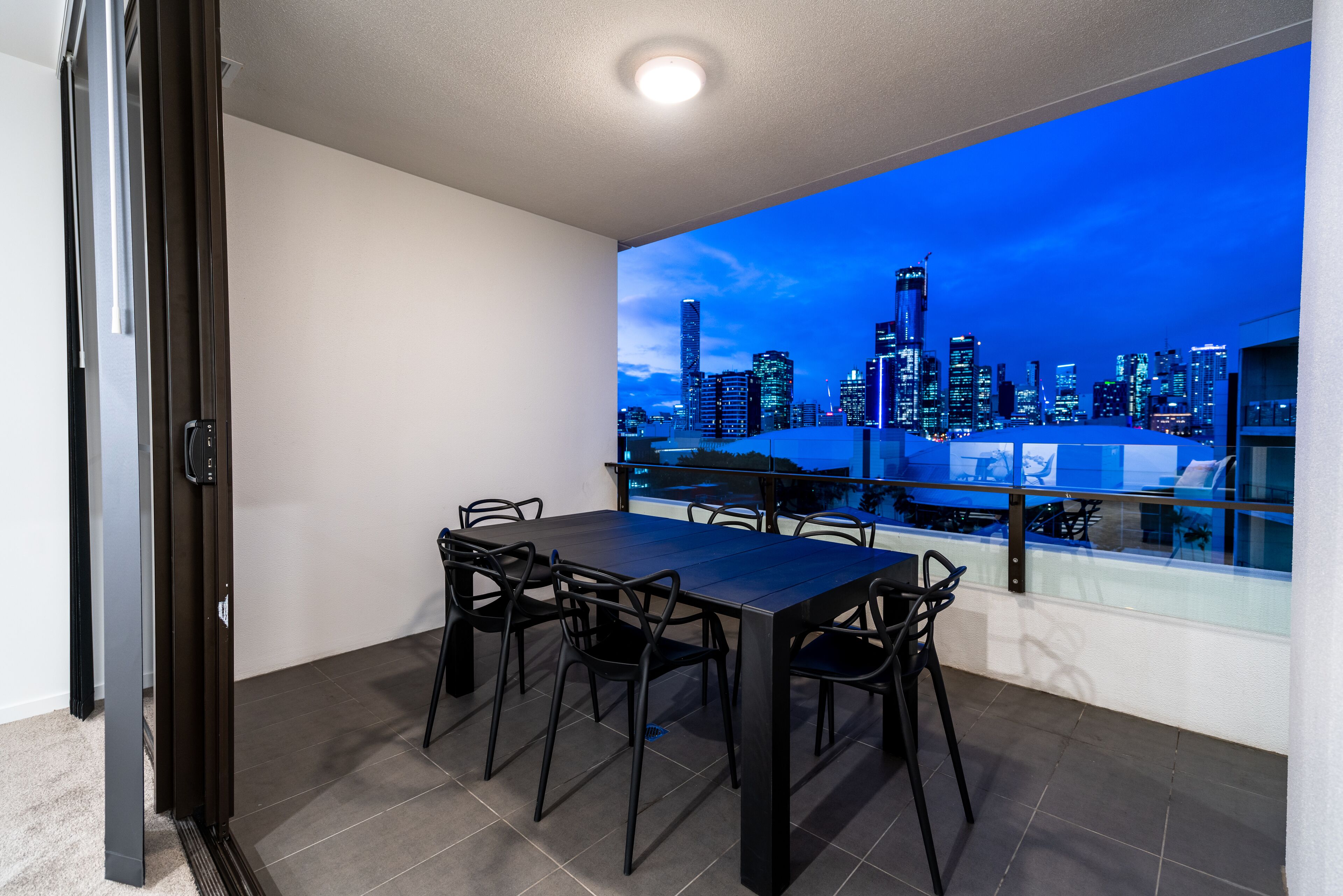 A modern dining area with a city view, a large table, and black chairs.