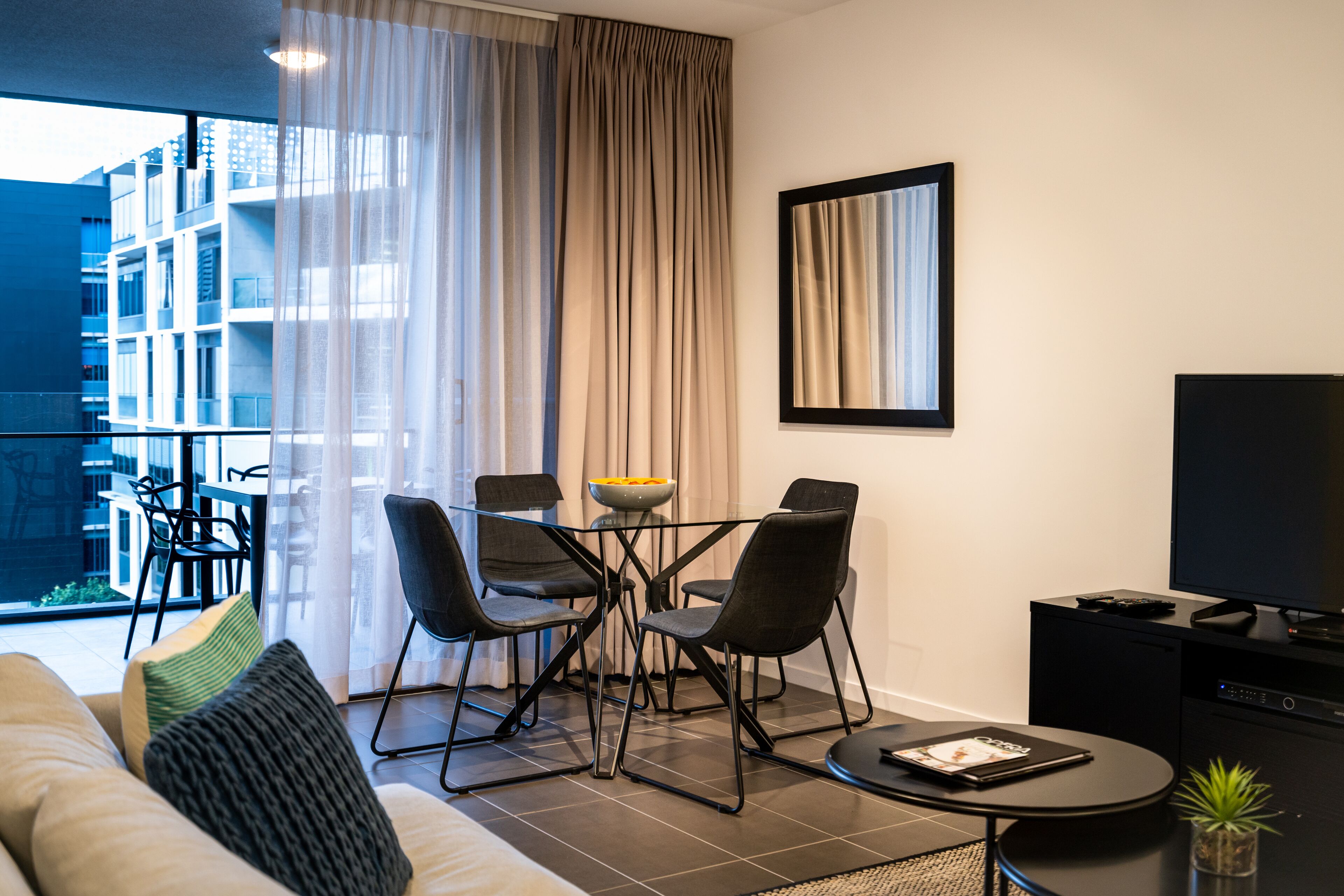 Un salon moderne comprenant un canapé, une table basse, un téléviseur et un coin repas avec des chaises et une table.