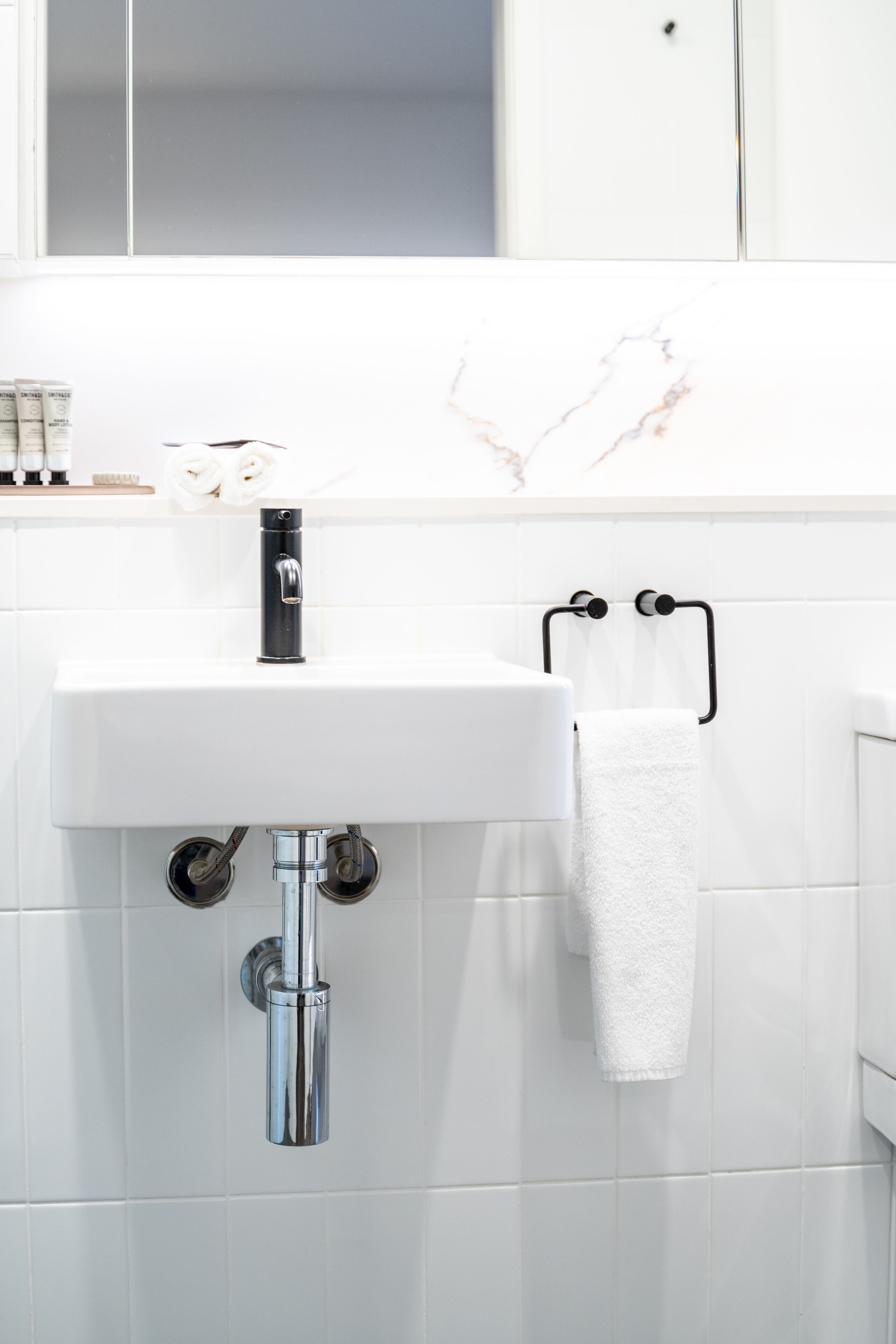 A bathroom with a white sink, chrome faucet, and towel rack.