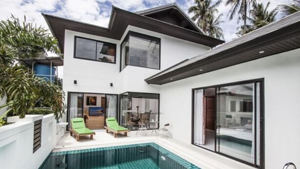Una moderna casa a due piani con piscina, patio coperto e ampie finestre.