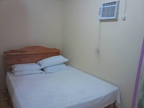 A small, single-bed room with a wooden headboard, white bedding, and a wall-mounted air conditioning unit. - Emok's Guest House - Hostel (Moalboal)