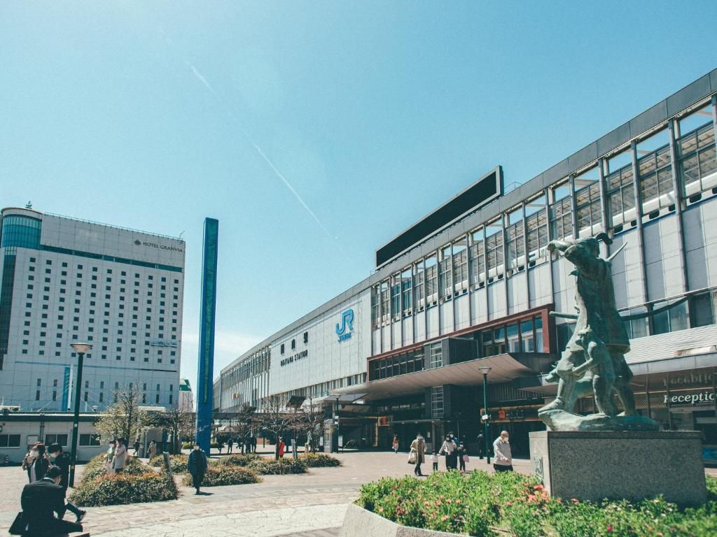 Un edificio moderno con un llamativo logotipo 'JR', una estatua y un cielo despejado.