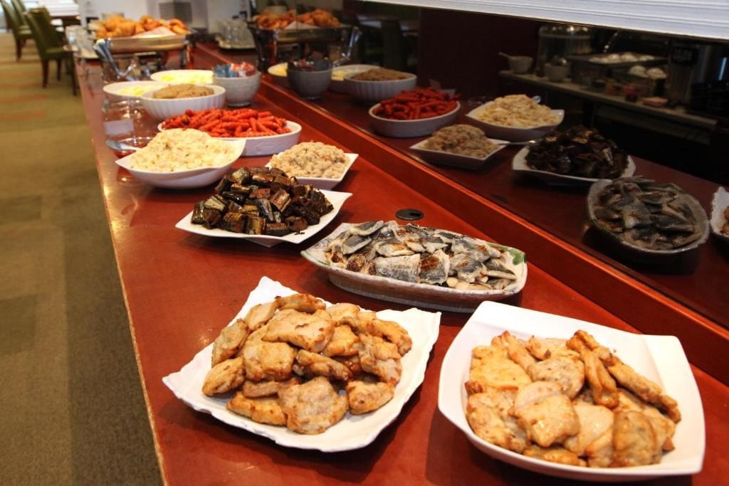 A buffet table with various dishes including seafood, rice, and vegetables.