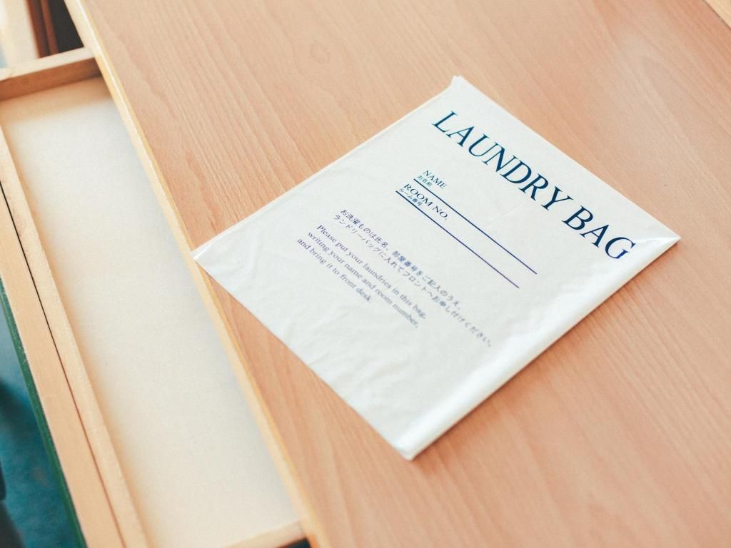 A white laundry bag with the text 'LAUNDRY BAG' and a form with fields for 'NAME' and 'ROOM NO.'