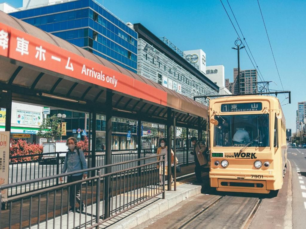 A bus stop with a shelter and a bus labeled 'Town Work' approaching.