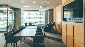 A conference room with a long table, chairs, a large TV screen, and a view of the outside. - Kuretake Inn Okayama (Okayama)