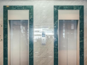 Deux portes d’ascenseur avec un panneau de commande au centre.