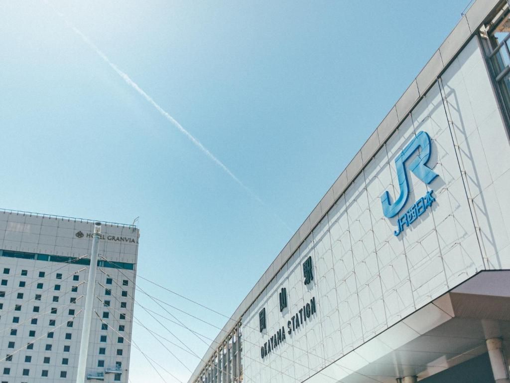 A JR station with a clear sky and a high-rise building in the background.