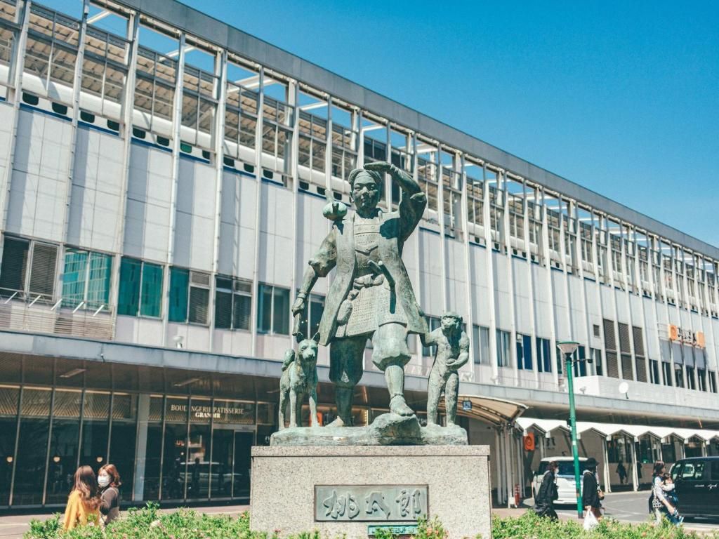A statue in front of a modern building with large windows and a sign that reads 'BOULANGERIE PASTISSERIE'.