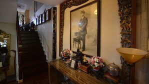 A staircase leading to a second floor, a framed portrait, and a table with decorative items. - Villa 91 Guesthouse (Bangkok)
