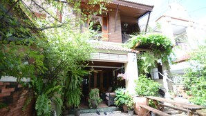 A courtyard with potted plants, a wooden bench, and a tiled floor. - Villa 91 Guesthouse (Bangkok)
