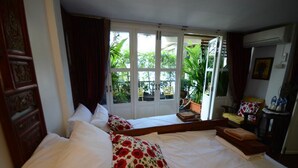 A hotel room with two beds, a large window with a view of the garden, and a small table with a chair. - Villa 91 Guesthouse (Bangkok)