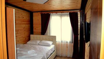 A wooden-paneled room with a bed, curtains, and a ceiling light.