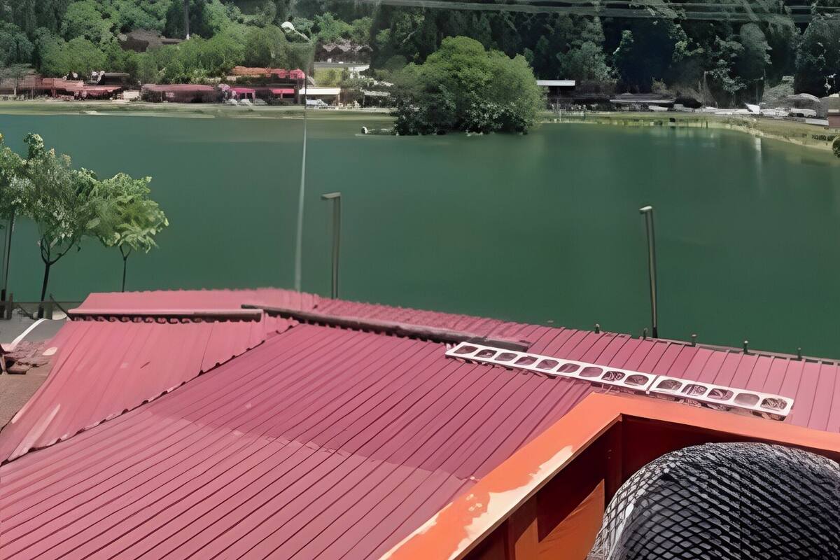 A view of a lake with a mountain in the background, a red-roofed structure in the foreground, and a clear blue sky.
