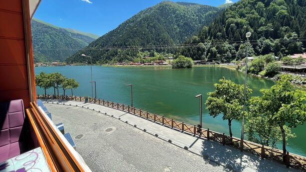 A view of a lake with mountains, a wooden fence, and a paved walkway. - Osmanli Suite (Çaykara)