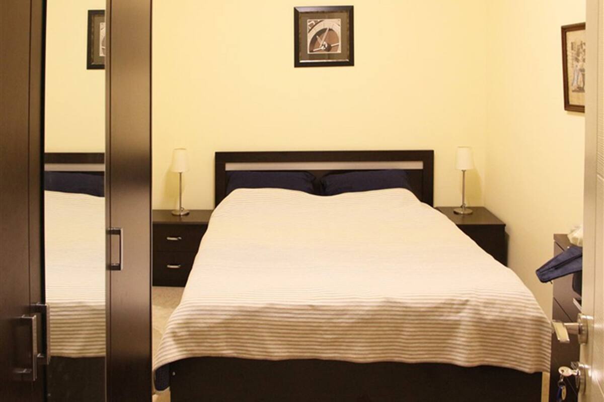 A hotel room with a bed, bedside tables, and a framed picture on the wall.