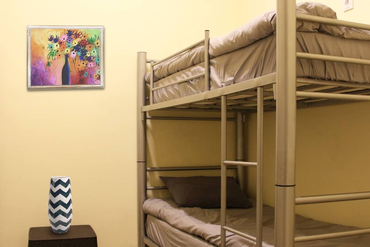 A bunk bed room with a small stool and a framed painting on the wall.