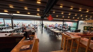 Un restaurante con mesas y sillas, vista al mar, y un letrero que dice 'GOOD TIMES'.
