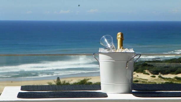 A bucket with champagne bottles and glasses on a table with a view of the ocean and beach. - Cintsa View (Great Kei)