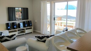 A living room with a sofa, chairs, a coffee table, a TV, and speakers. - Cintsa View (Great Kei)