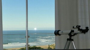 A telescope on a tripod by a window overlooking the ocean. - Cintsa View (Great Kei)