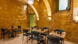 A dining area with stone walls, green doors, and tables set for four. - The Vincent Boutique Hotel, BW Premier Collection (Valletta)
