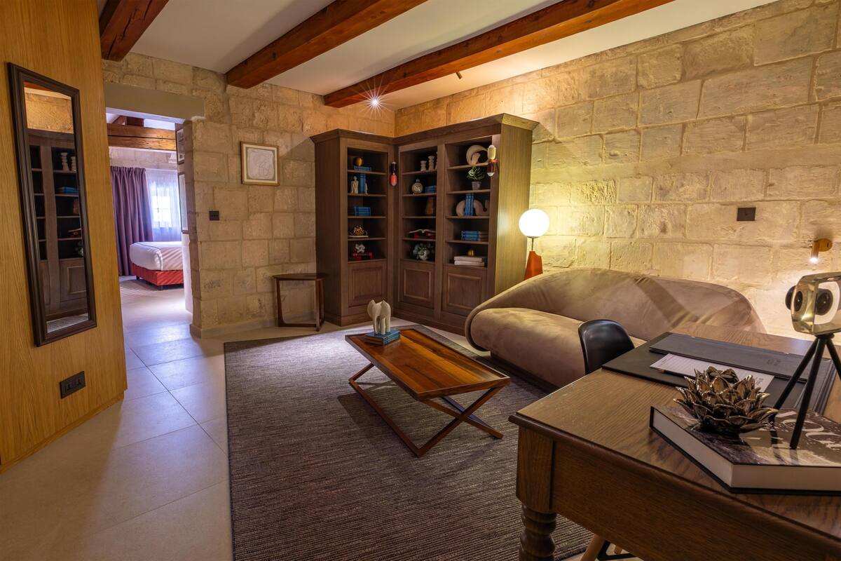 A cozy living room with a sofa, a wooden coffee table, a bookshelf, and a lamp.