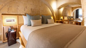A room with a large bed, a wooden desk, and a stone wall. - The Vincent Boutique Hotel, BW Premier Collection (Valletta)