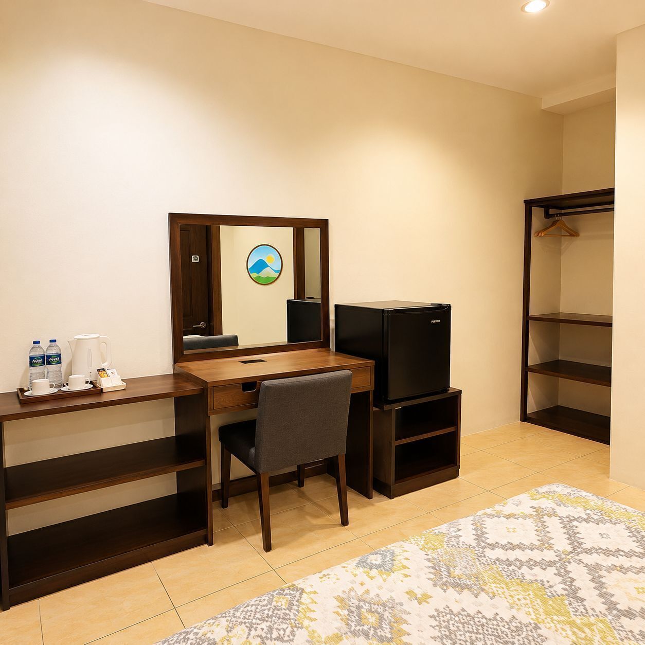 A hotel room with a desk, chair, mirror, television, and a wardrobe.