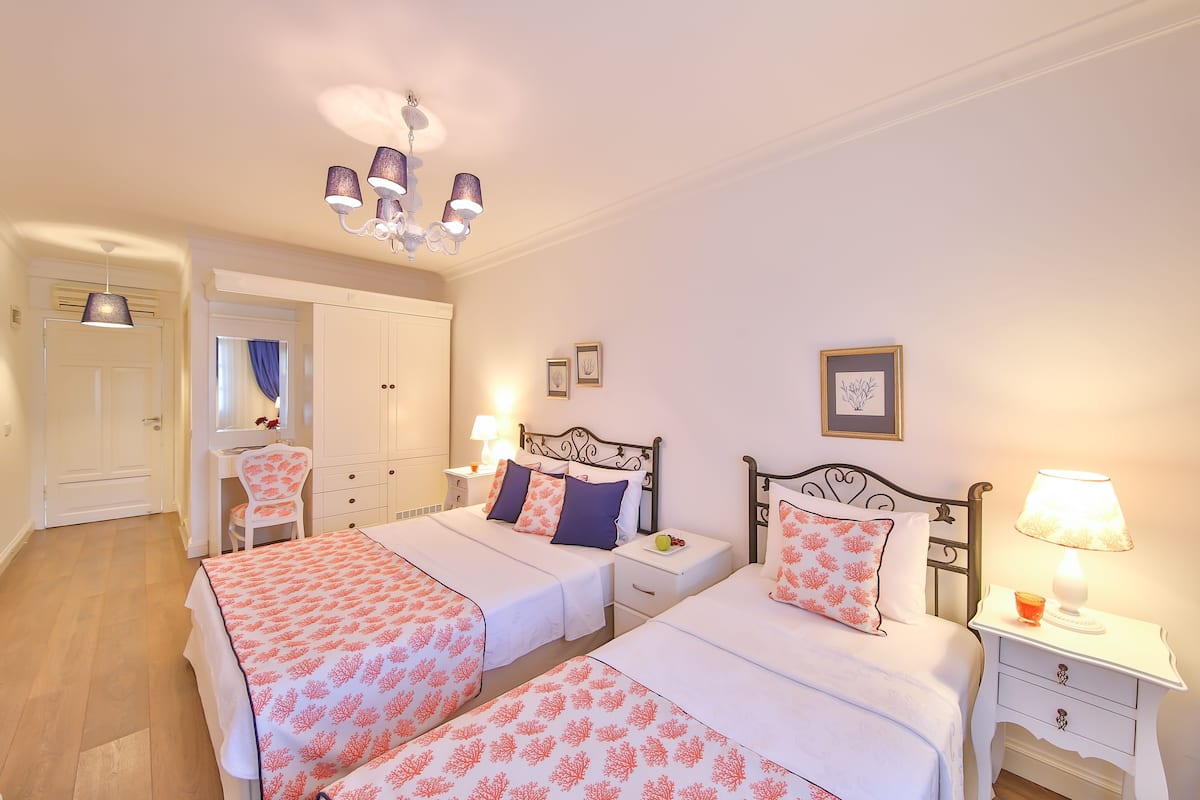 A double room with two beds, a desk, a chair, and a wardrobe.