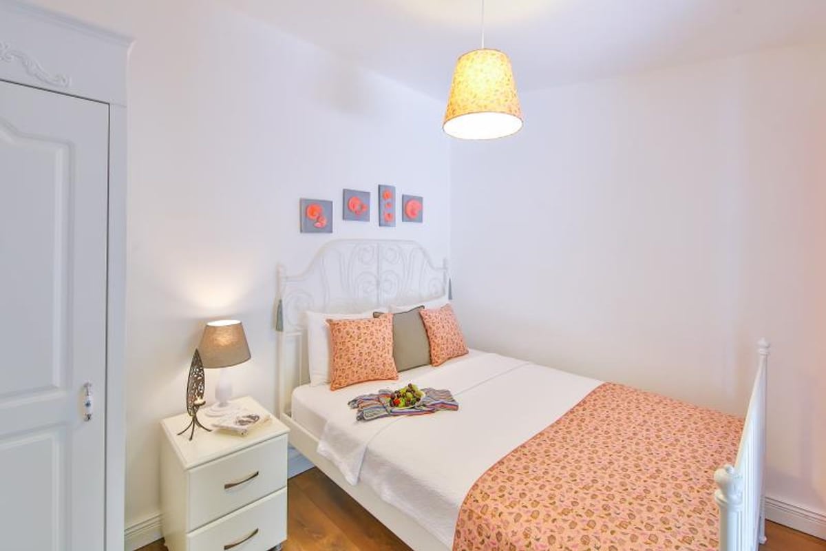 A bedroom with a bed, a bedside table, a lamp, and a hanging light fixture.