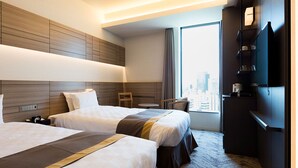 Habitación de hotel con dos camas, vistas a la ciudad, un escritorio y un televisor.