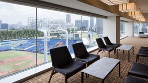 Habitación de hotel con un ventanal que ofrece vistas a un estadio de béisbol y al paisaje urbano.