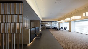 Un moderno vestíbulo de hotel con mostrador de recepción, zona de estar y amplios ventanales que dejan entrar luz natural.