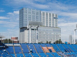 Un estadio con asientos azules y un edificio moderno al fondo.