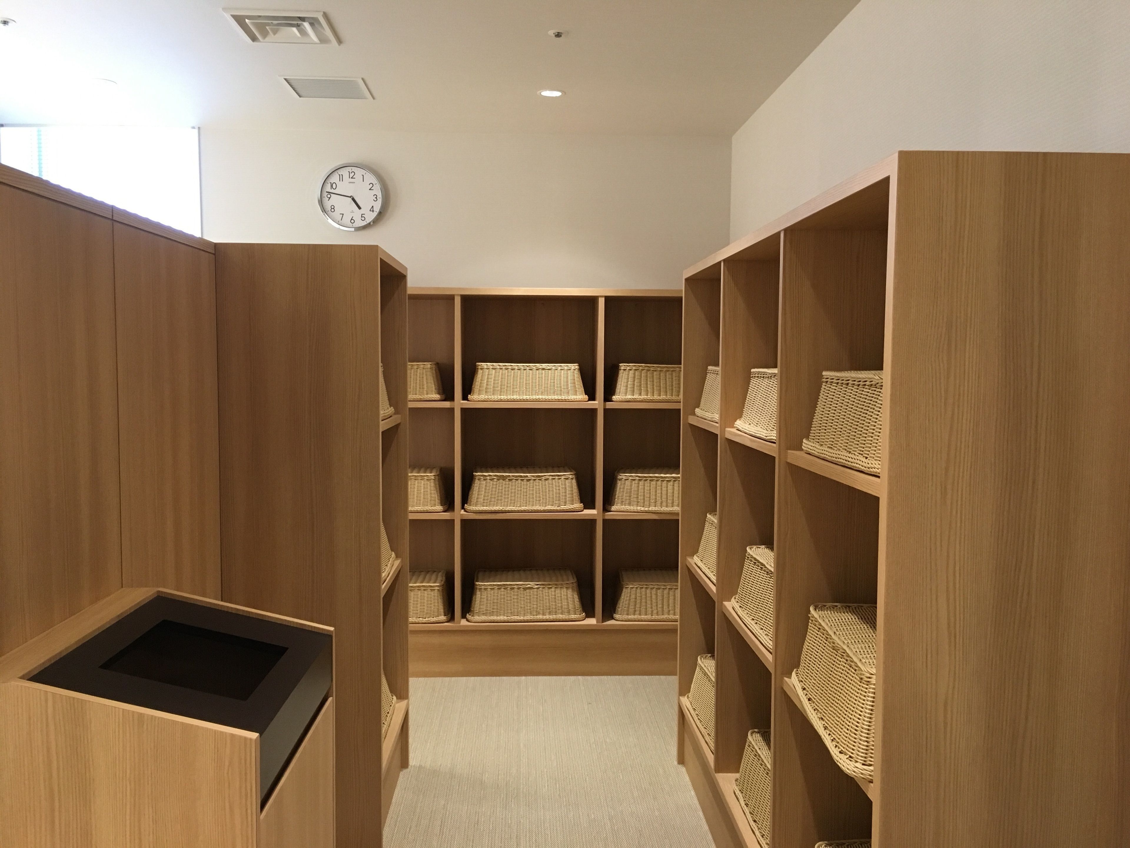 A wooden storage room with shelves containing wicker baskets.