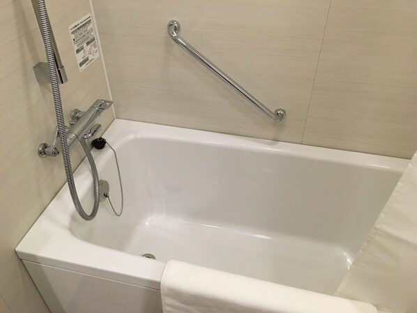 Une baignoire blanche équipée d’une douchette à main, d’une barre d’appui et d’une serviette.