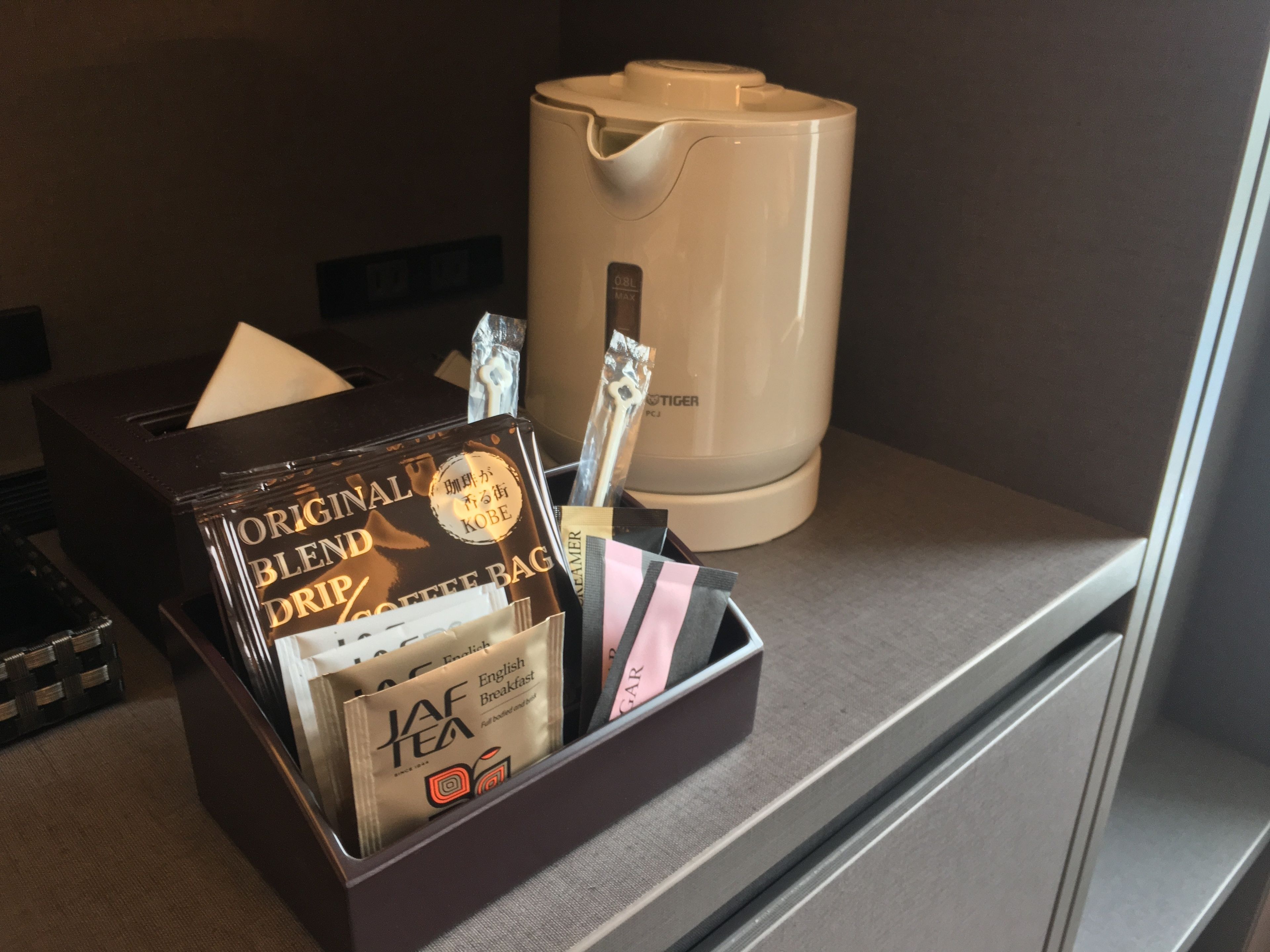 A coffee maker and a tray with coffee bags and a tea bag on a counter.