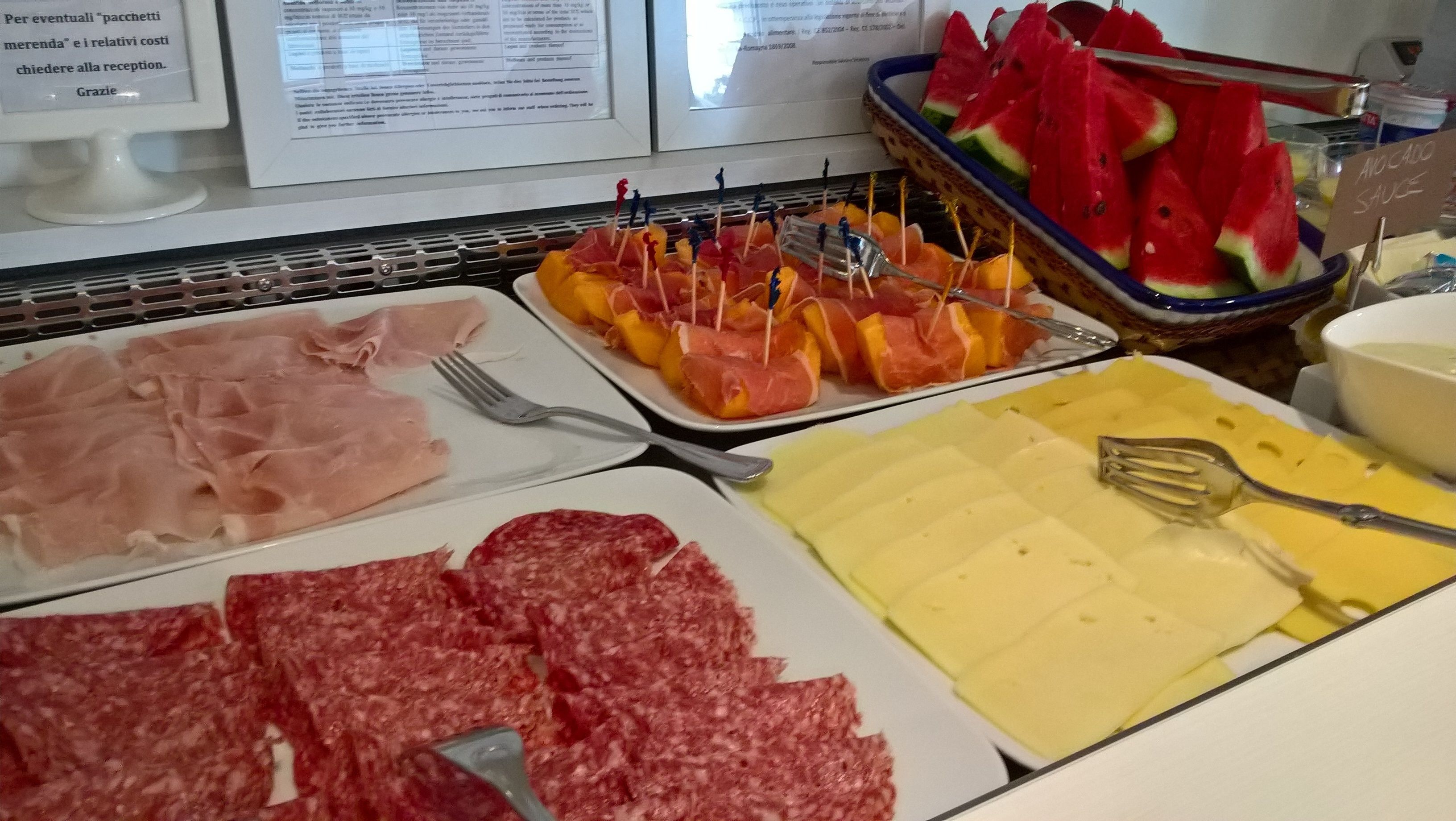 A buffet with various food items including sliced meats, cheese, and fruits.