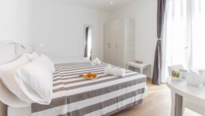 Ett hotellrum med en stor säng, ett litet sängbord, ett fönster med gardiner och utsikt över omgivningarna.